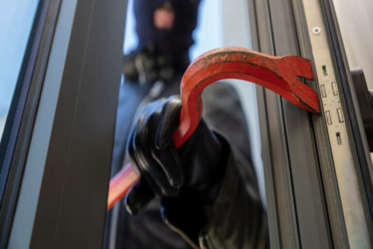Bandit In Balaclava Holding A Crowbar To Break A Glass