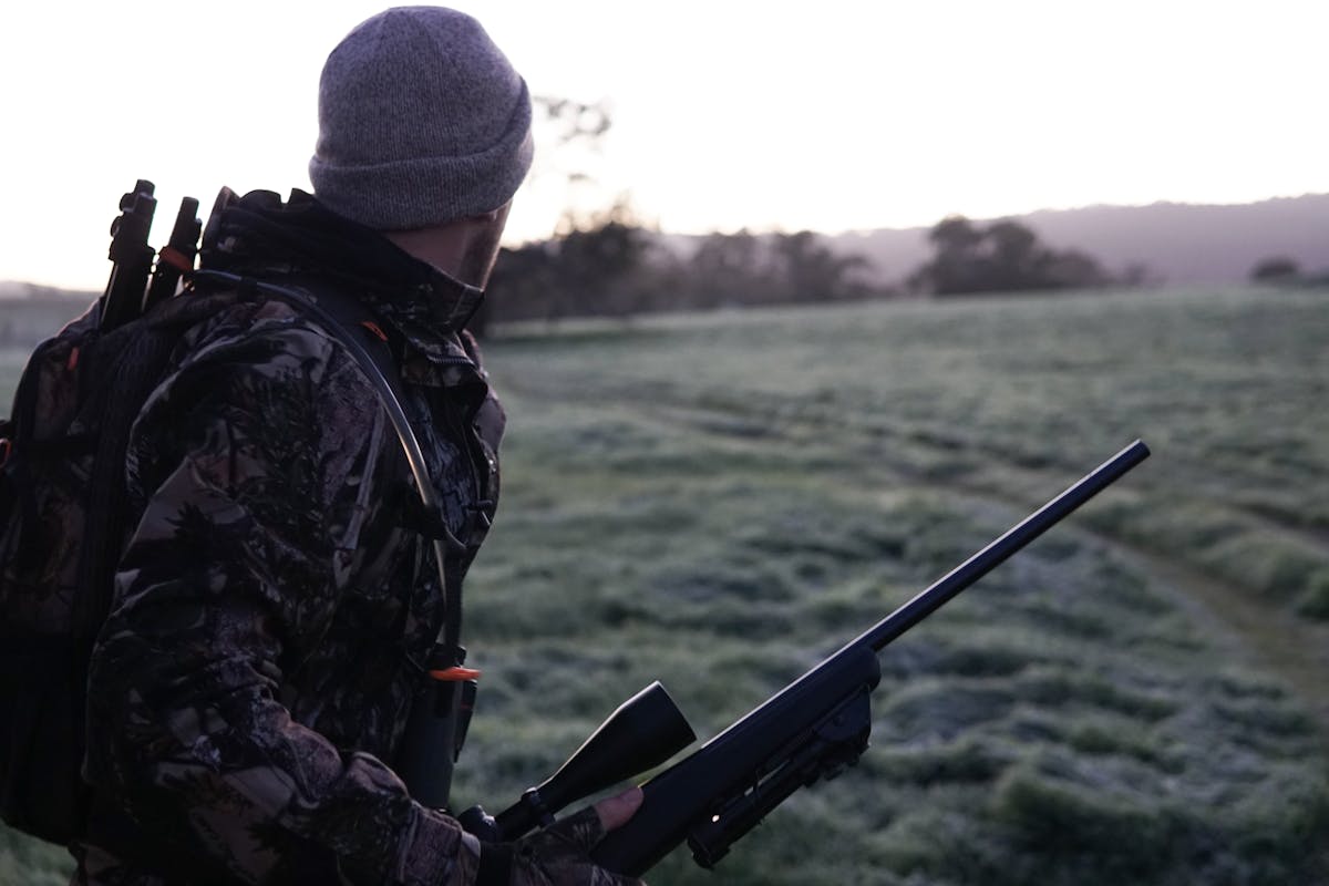 Man Wearing Gray and Black Camouflage Jacket Holding Rifle