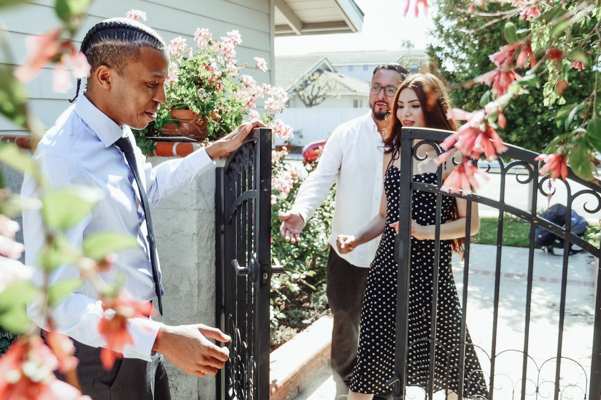 Man in Dress Shirt Holding the Gate for a Couple